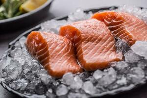 en porciones crudo salmón filetes en hielo en plato con limón y Romero foto