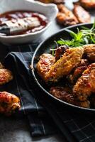 Chicken wings barbeque in a cast iron baking dish with BBQ sauce and rosemary photo