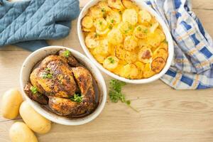 Roasted whole chicken in bowl with potatoes on home kitchen table - Top of view photo