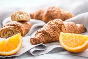 Fresco mantecoso cruasanes con dulce naranjas en cocina servilleta foto