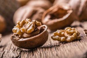 Walnut. Walnut kernels and whole walnuts on rustic old oak table photo