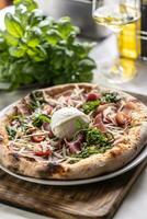 Round buffalo mozzarella on top of a ham, tmatoes and rocket pizza with crusty edges photo