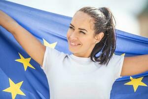 Smiling beautiful woman holding an EU flag looking to the side photo