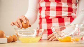 Detail of woman's hands separating egg yolks from the whites into two glass bowls photo