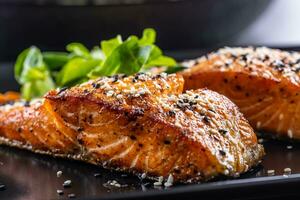 Two salmon fillets baked until crispy with sesame - Close up photo