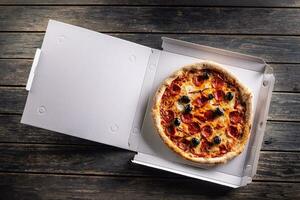 Pizza en un cartulina caja en mesa Listo a cliente. foto