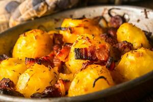 papas. asado patatas con tocino cebolla y salchichas en antiguo roble mesa foto