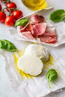 Mozzarella cheese olives olive oil  tomatoes prosciutto basil leaves -  ingredients italian or mediterranean cuisine photo