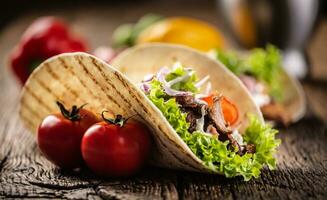 Open meat and veg tortilla on a rustic wooden board photo