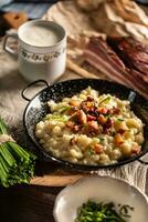 Bryndzove halusky, the national food of Slovakia, served with bacon, chives and a cup of sour milk photo