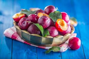 Plums. Fresh juicy plums in a bowl on a wooden or concrete board photo