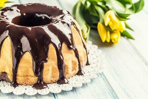 Delicious holiday slovak and czech cake babovka with chocolate glaze. Easter decorations - spring tulips and eggs photo