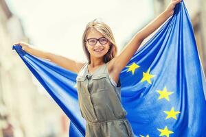 EU Flag. Cute happy girl with the flag of the European Union. Young teenage girl waving with the European Union flag in the city photo