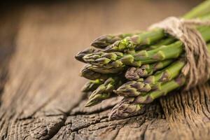 Bunch of fresh asparagus on rustic oak table photo
