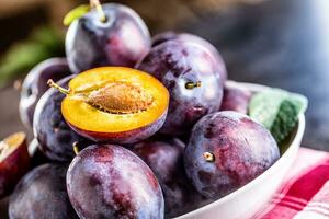 Plums. Fresh juicy plums in a bowl on a wooden or concrete board photo