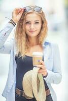 Young blonde woman drinking coffee somewhere in the city streets photo