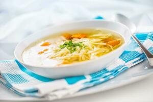 Lunch setting table with chicken or beef soup with noodles carrot and herbs photo