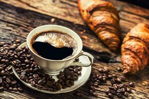 Coffee. Cup of coffee croissants and coffee beans. Vintage cup and old oak table photo