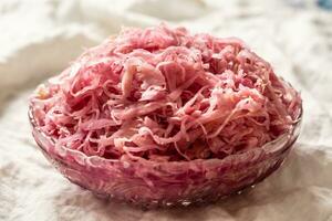 Sour cabbage served in a glass bowl on a rustic tablecloth photo