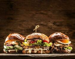 Front view on three large, beef salmon and kebab burgers stuffed with fresh vegetable salad and dressing photo