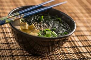 tradicional japonés sopa miso con tofu algas marinas palillos y joven cebolla foto