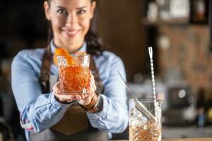 antiguo pasado de moda bebida en ornamental vaso Ofrecido por un hembra barman en un pub foto