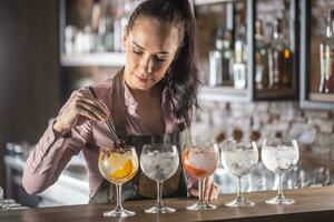 Barmaid is preparing a selection of five various gin tonic drinks on the bar photo