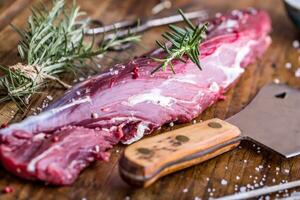 Raw beef meat. Raw beef tenderloin steak on a cutting board with rosemary pepper salt in other positions. photo