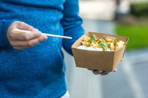 Young man's hands holding lunch in a box of recycled paper photo