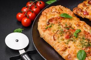 Delicious oven fresh flatbread pizza with cheese, tomatoes, sausage, salt and spices photo