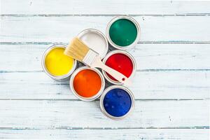 Top of view full of multicolored paint cans with brush on table. photo