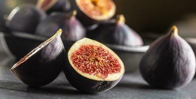 A few figs in a black bowl on an dark concrete table photo