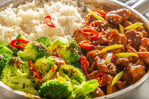 Spicy teriyaki chicken with steamed broccoli and rice in a pot photo