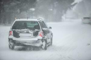 Liptov, Slovakia - JANUARY 30, 2022. Car covered in snow driving in snowstorm on a cold winter day photo