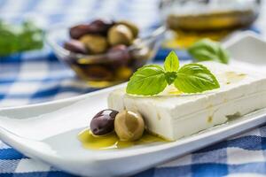 Greek cheese feta with olive oil olives and basil leaves photo