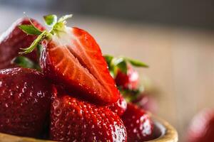 Juicy washed strawberries in wooden bowl on kitchen table photo