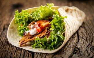 Tortilla with meat, tomato, salad, onion and cream photo