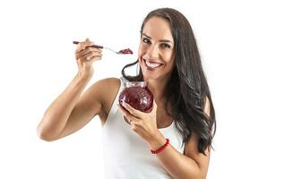 Widely smiling attractive woman holding a spoon full of delicious berry jam. Isolated background photo