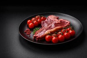 Raw fresh juicy beef t-bone steak with salt, spices and herbs photo