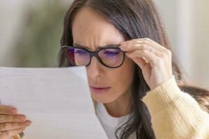 The woman has vision problems and reads the letter very close to her eyes and glasses photo