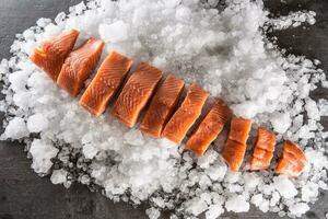 salmón filetes en porciones en hielo y vacío cocina tablero. foto