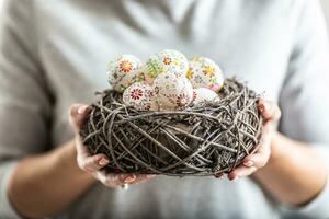 Birds nest full of colorful easter eggs held in womens hands photo