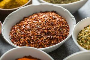 Ground chilli pepper and variety spices and herbs in bowls photo