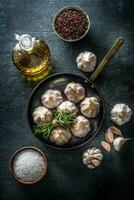 Garlic cloves and bulb in pan with fresh rosemary olive oil salt and spice on concrete table photo