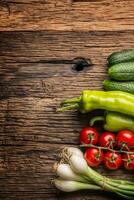 Fresh vegetable onion cucumber pepper and tomatoes on rustic oak table photo