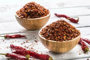 Dried and crushed chili peppers in wooden bowles photo