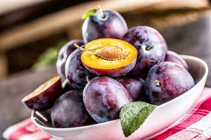 Plums. Fresh juicy plums in a bowl on a wooden or concrete board photo