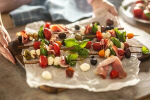 Female hands holding board with mini caprese skewers italian or mediterranean appetizer photo