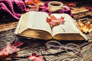 taza de café antiguo libro lentes y otoño hojas. foto