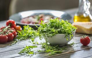 Fresh arugula salad in white dish on wooden table photo